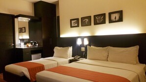 A hotel room with two beds, a desk with a mirror, a coffee maker, and framed pictures on the wall. - Hotel Esse Davao (Davao)
