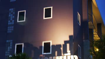 Un bâtiment moderne à la façade sombre et doté de nombreuses fenêtres. Le mot « Hôtel » est clairement affiché sur la façade.