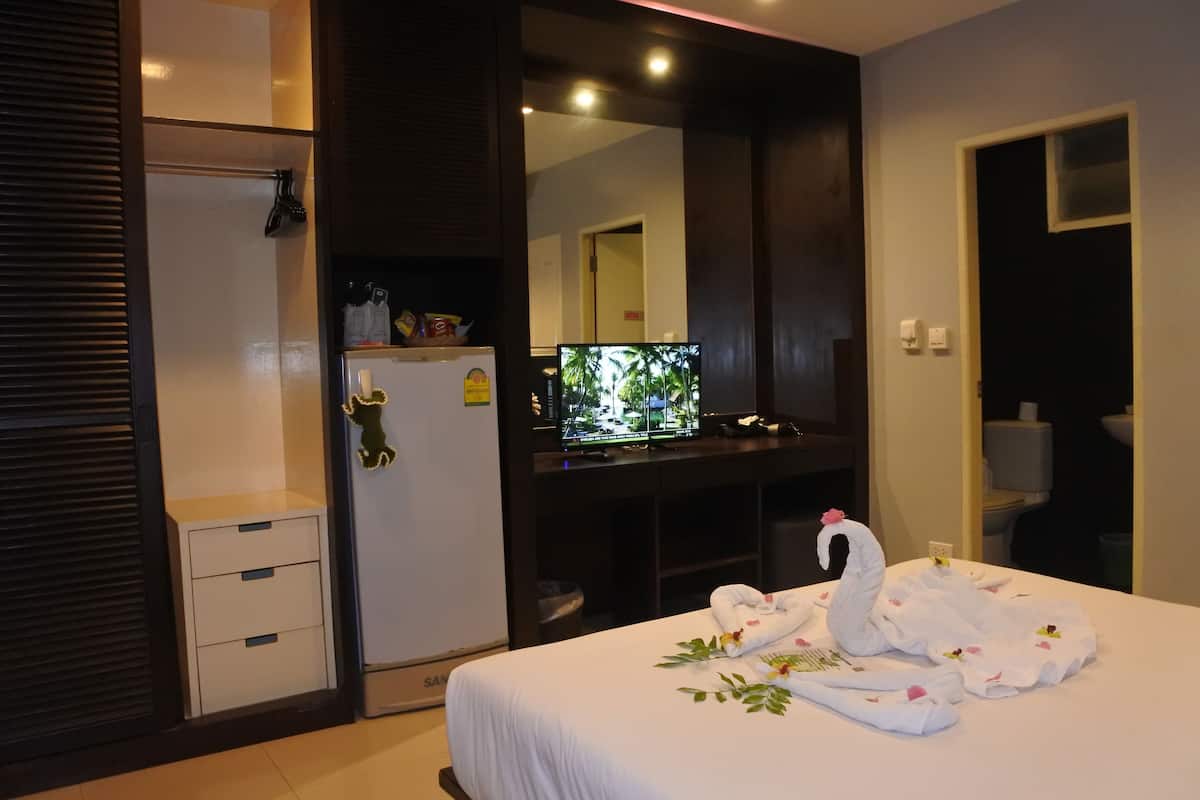 A hotel room with a bed, a television, a minibar, and a bathroom visible through an open door.
