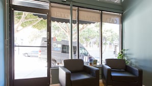A room with two black chairs, a wooden floor, and a large window with a view of parked cars and trees outside.