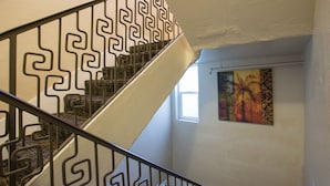 A staircase with a geometric railing design and a painting on the wall.
