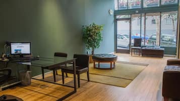Una sala de conferencias con una mesa de vidrio, sillas, una computadora, una planta y vistas a la calle a través de grandes ventanales.
