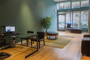 A conference room with a glass table, chairs, a computer, a plant, and a view of the street through large windows. - Casa Loma Hotel (San Francisco)