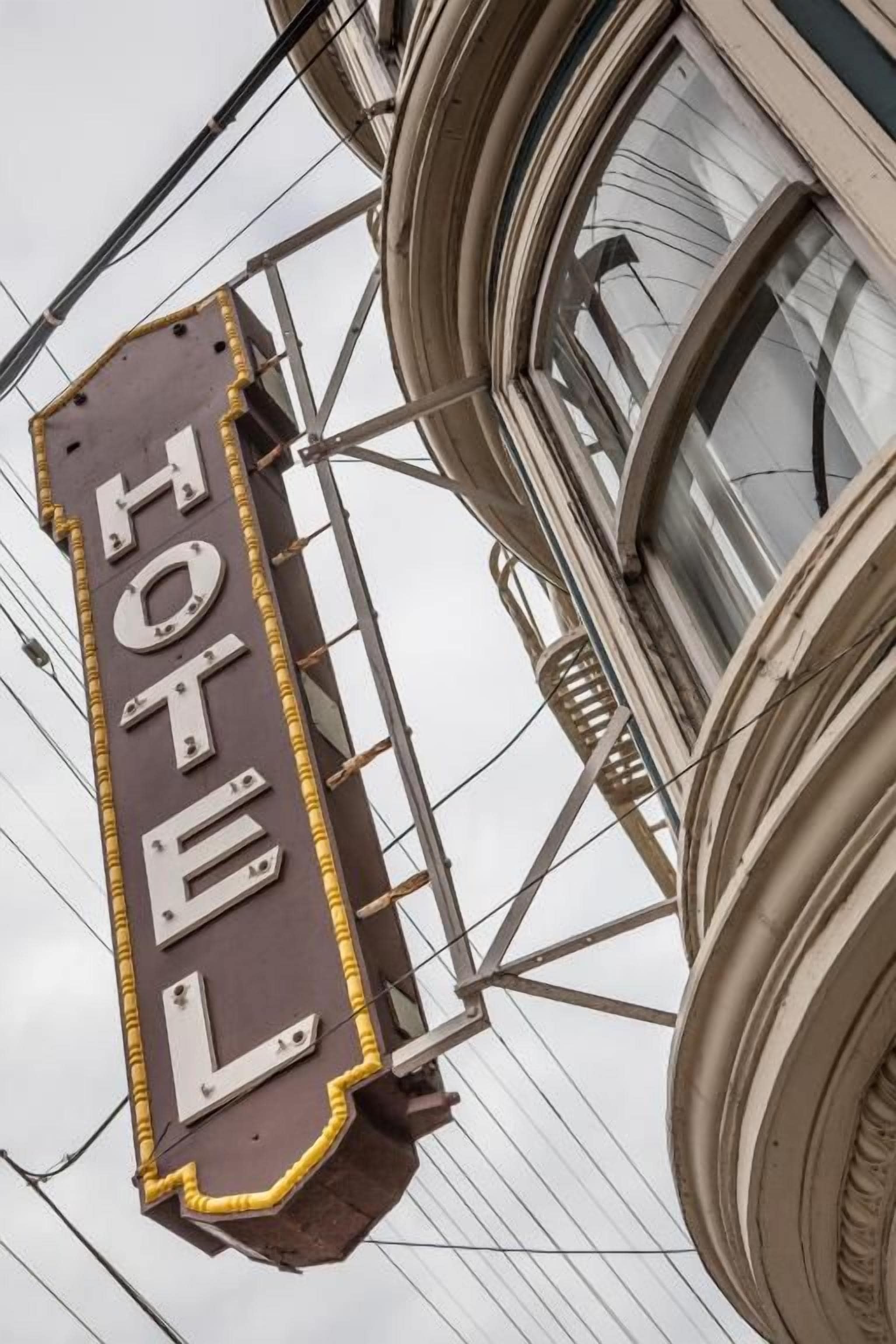 Une enseigne d’hôtel avec le mot « HÔTEL » écrit en grandes lettres, fixée sur une structure métallique.