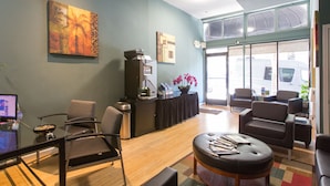 A modern lobby with a reception desk, seating area, and artwork on the walls.