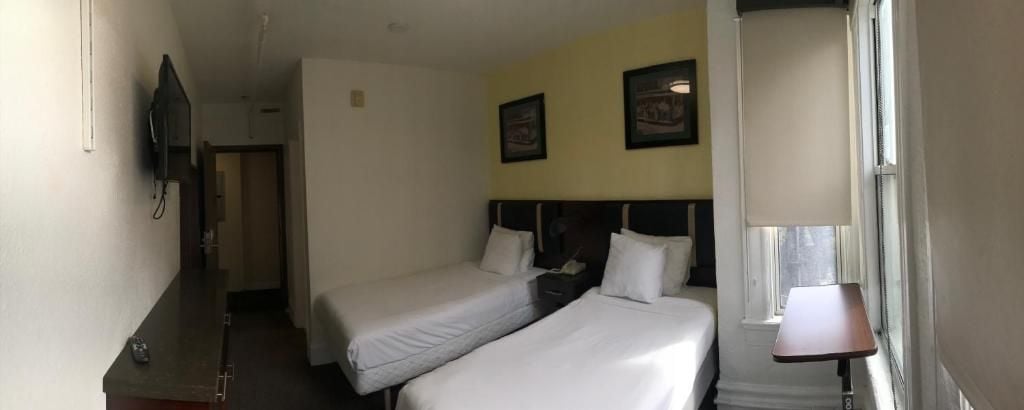 A hotel room with two beds, a desk, a TV, and a window with a view.