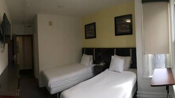 A hotel room with two beds, a desk, a TV, and a window with a view.