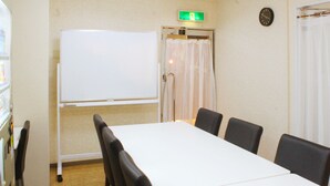 Een vergaderruimte met een whiteboard, een klok en een gordijn.