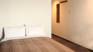Een hotelkamer met een bed, een houten vloer en een spiegel aan de muur.