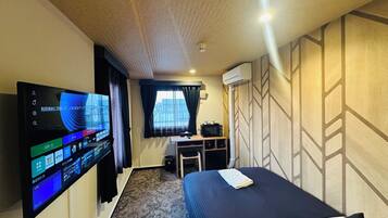 A hotel room with a bed, a desk, a television, and a window with curtains.