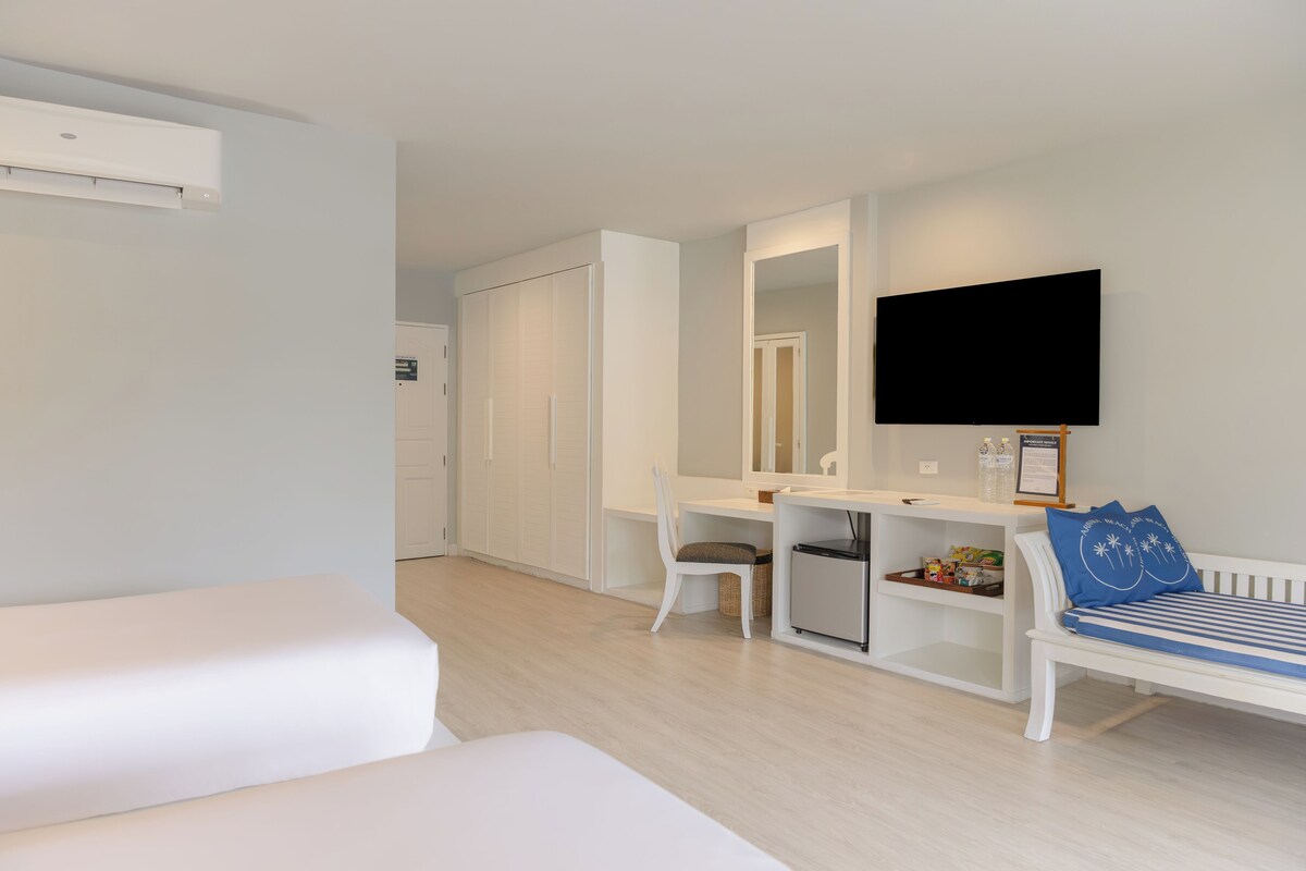 Una habitación de hotel con cama, escritorio, silla, televisor y armario.