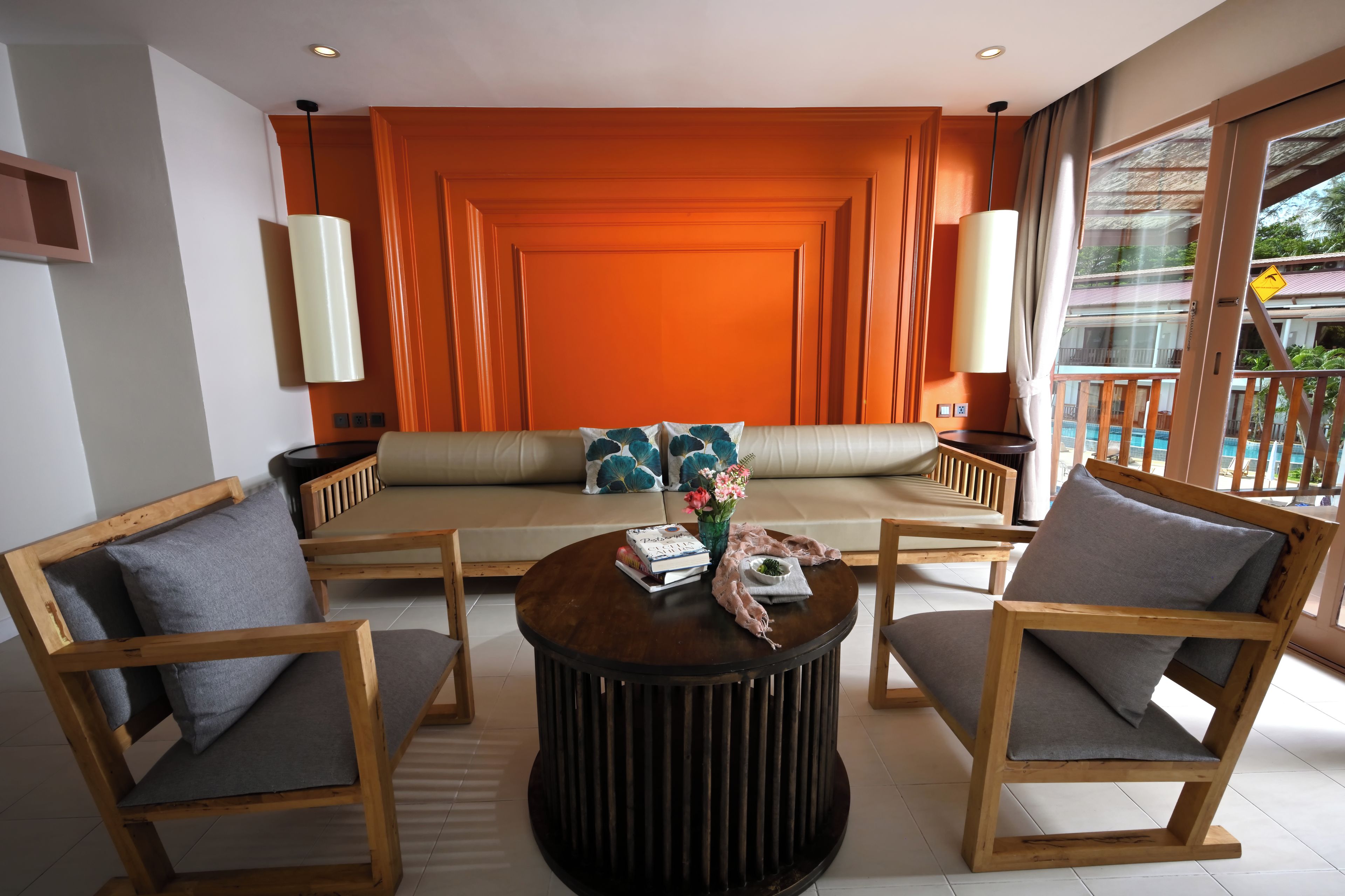 Un salon moderne avec un canapé, deux fauteuils, une table basse et une vue sur une piscine.