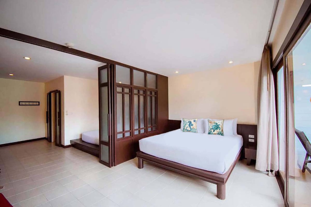Habitación de hotel con una cama grande, una puerta corrediza de vidrio y vistas al exterior.
