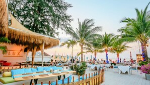 An outdoor dining area with thatched-roof structures and palm trees. - Arinara Beach Resort Phuket (Choeng Thale)