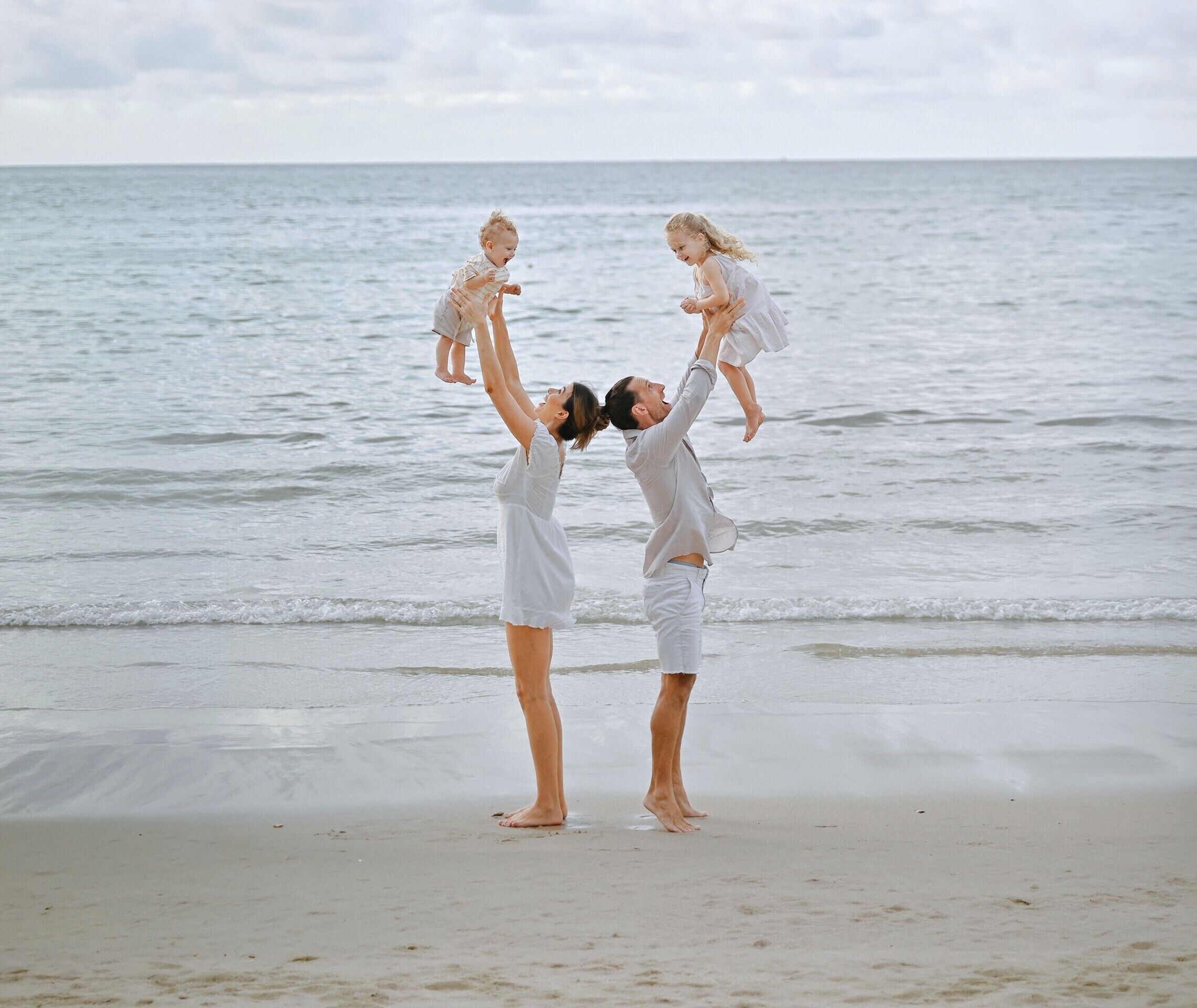 Een strandscène met twee volwassenen en twee kinderen.