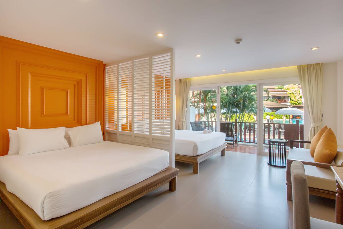 Quarto de hotel com uma cama grande, um sofá e uma varanda com área de estar externa.