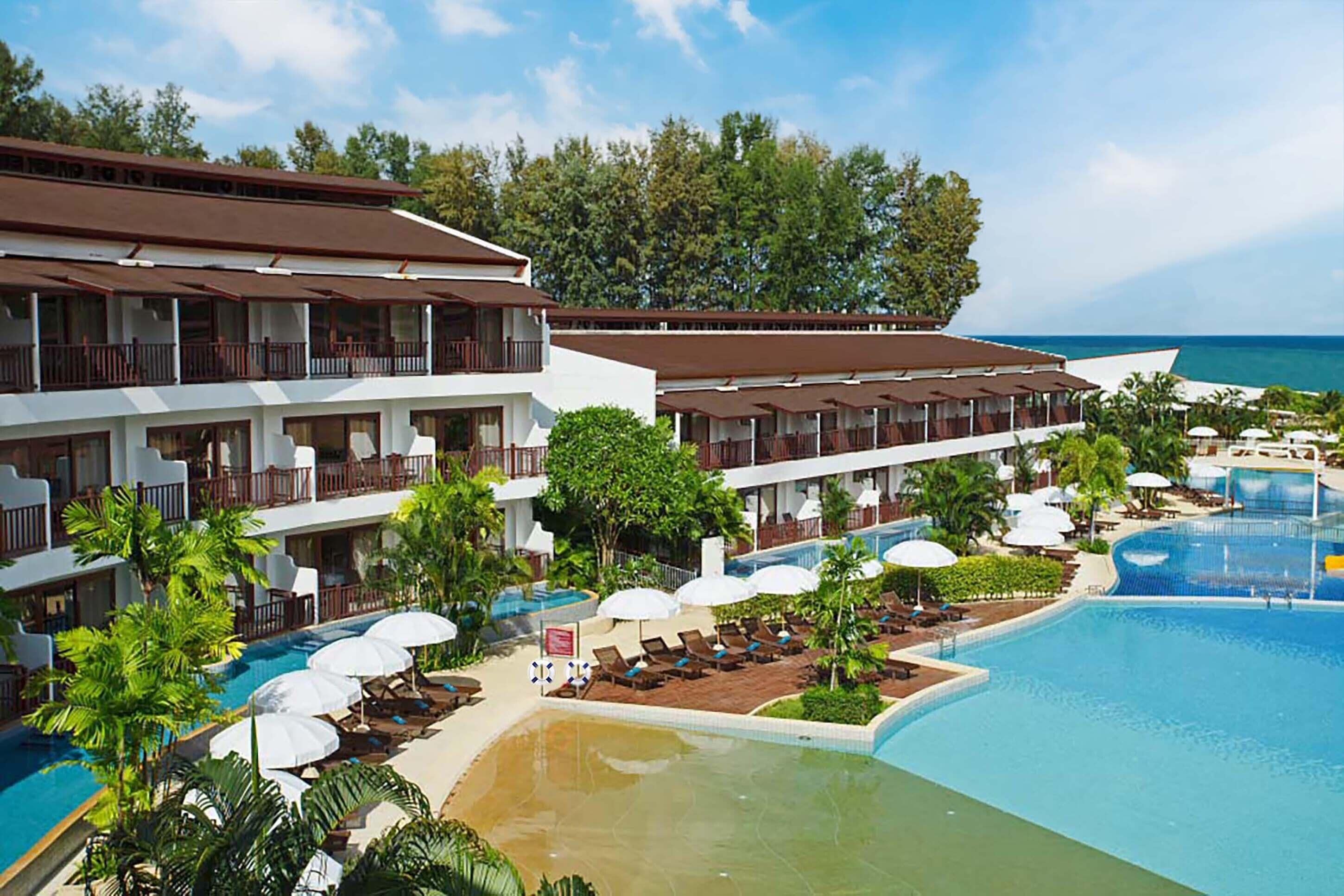 A hotel with multiple balconies, a swimming pool, and a view of the ocean.