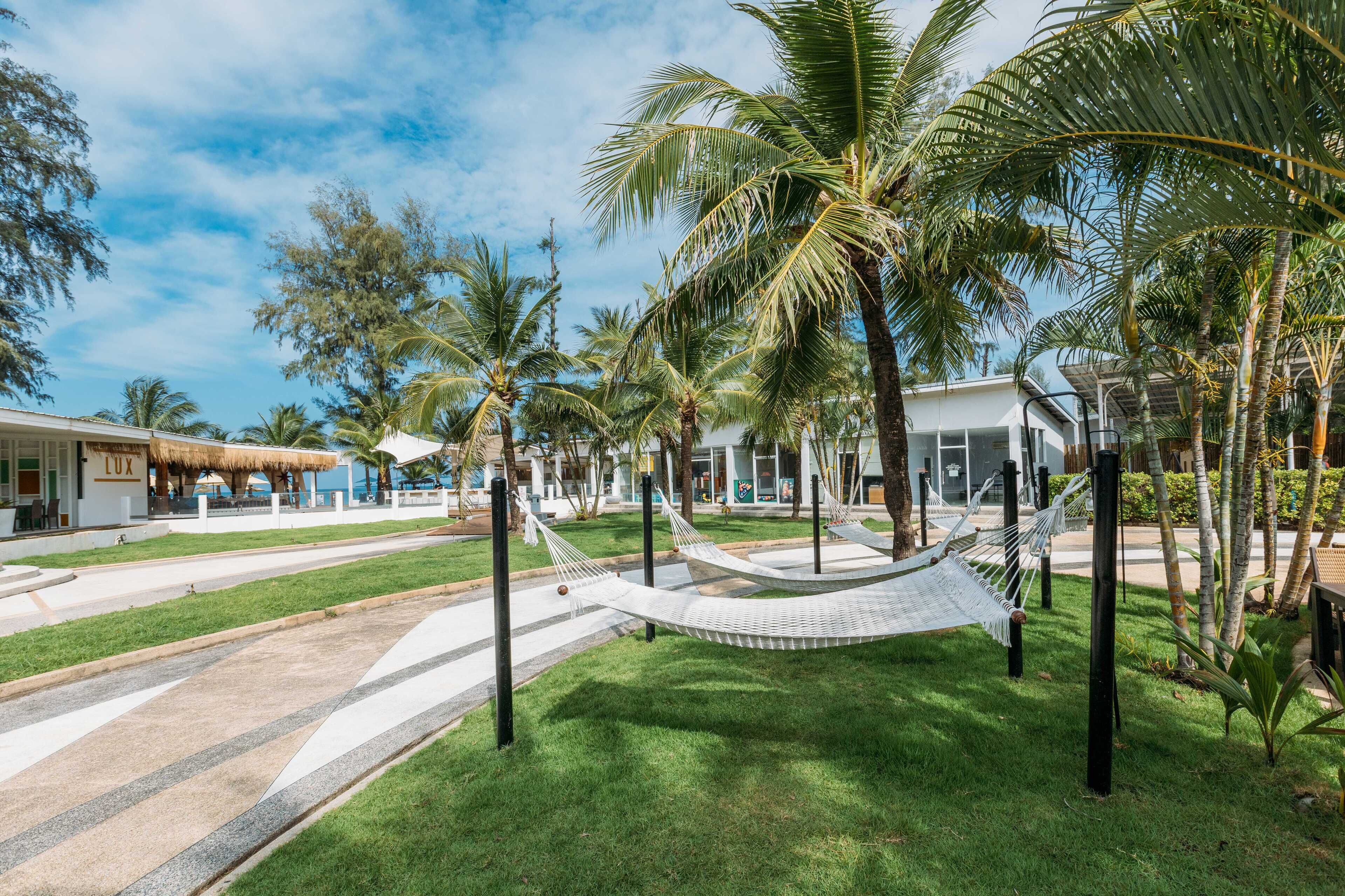 Un resort tropical con palmeras, una hamaca y un edificio que dice "LUX".