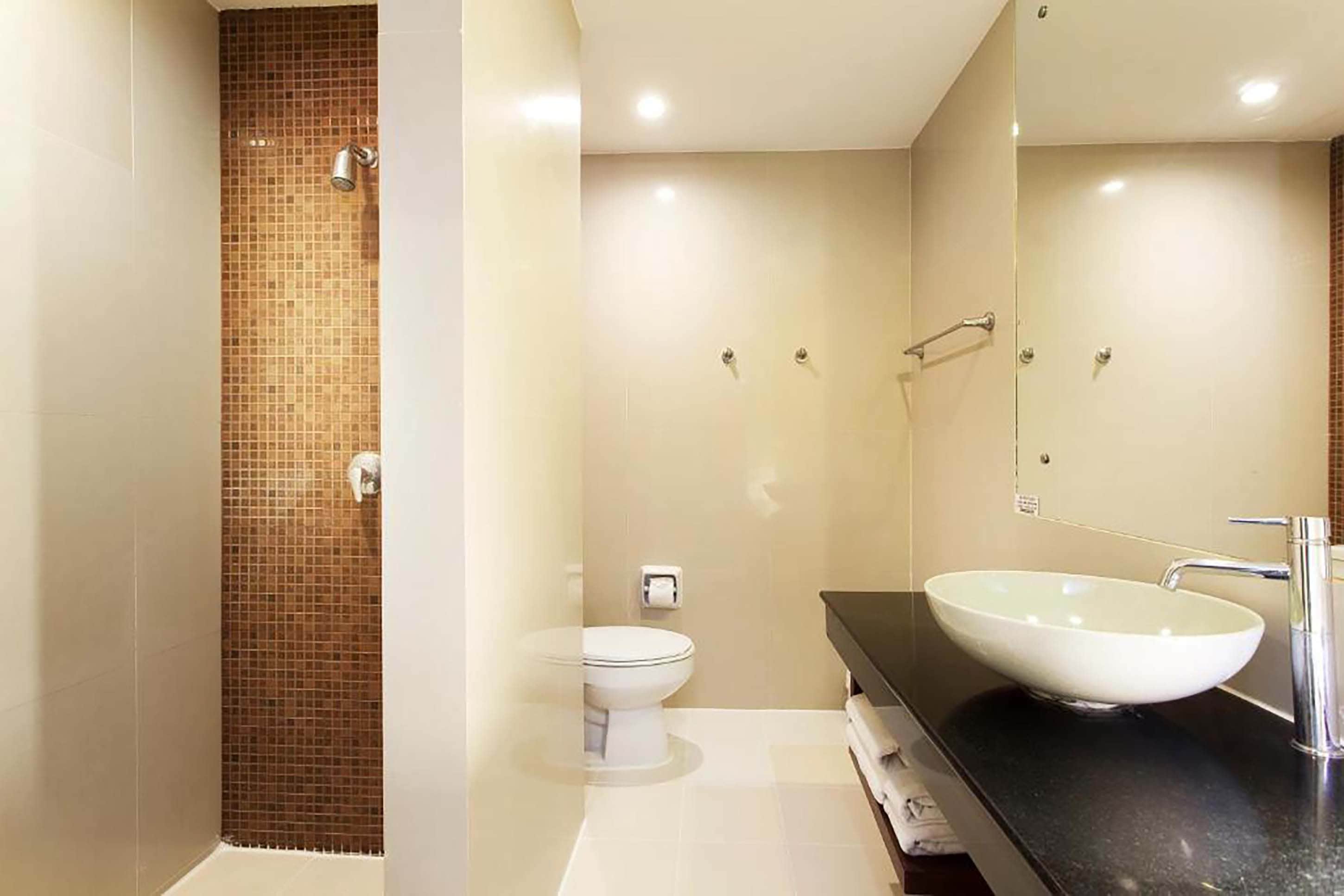 A modern bathroom with a large mirror, a white sink, and a shower area.