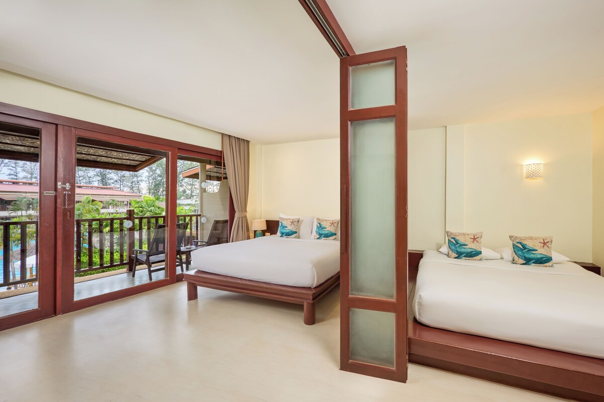 Habitación de hotel con dos camas, un balcón y vistas a zonas verdes, además de una puerta corrediza de vidrio.