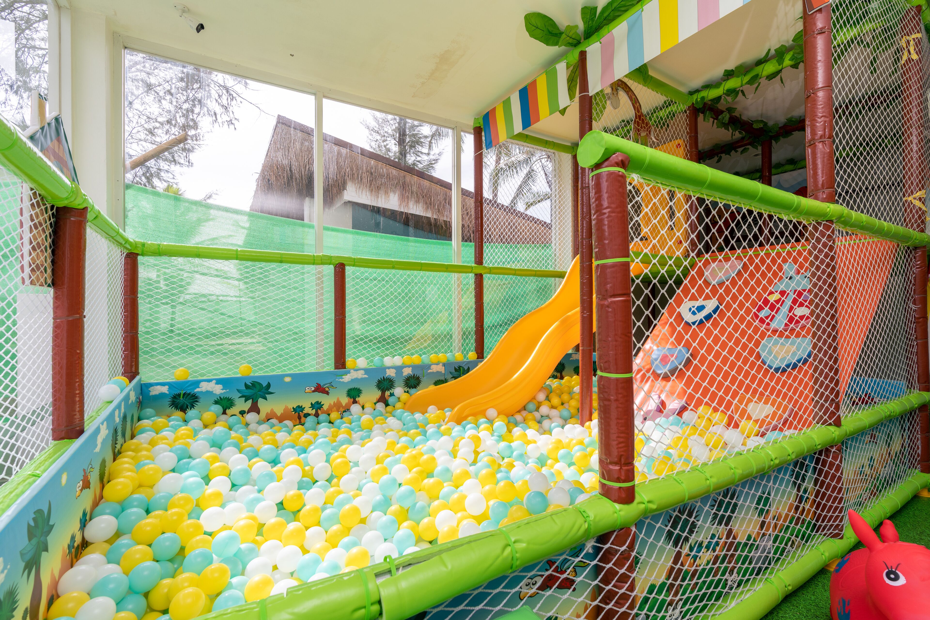 A children's play area with a ball pit, a slide, and a netted enclosure.