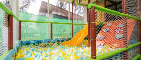A children's play area with a ball pit, a slide, and a netted enclosure.