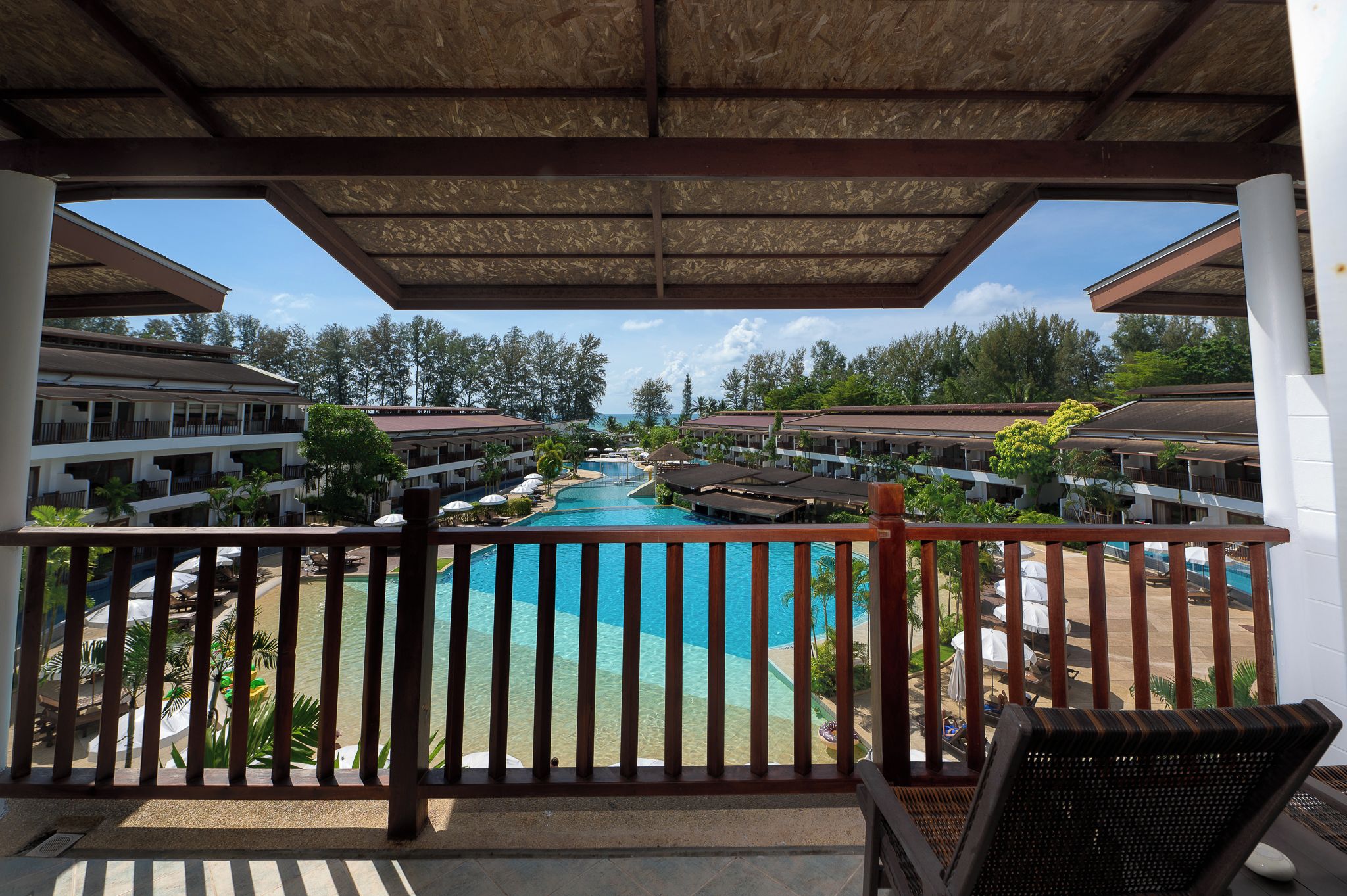 Varanda de hotel com vista para uma piscina e edifícios do resort.