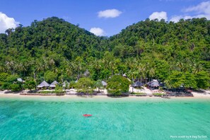 Un resort tropical con bungalows sobre el agua, aguas turquesas cristalinas y exuberante vegetación.