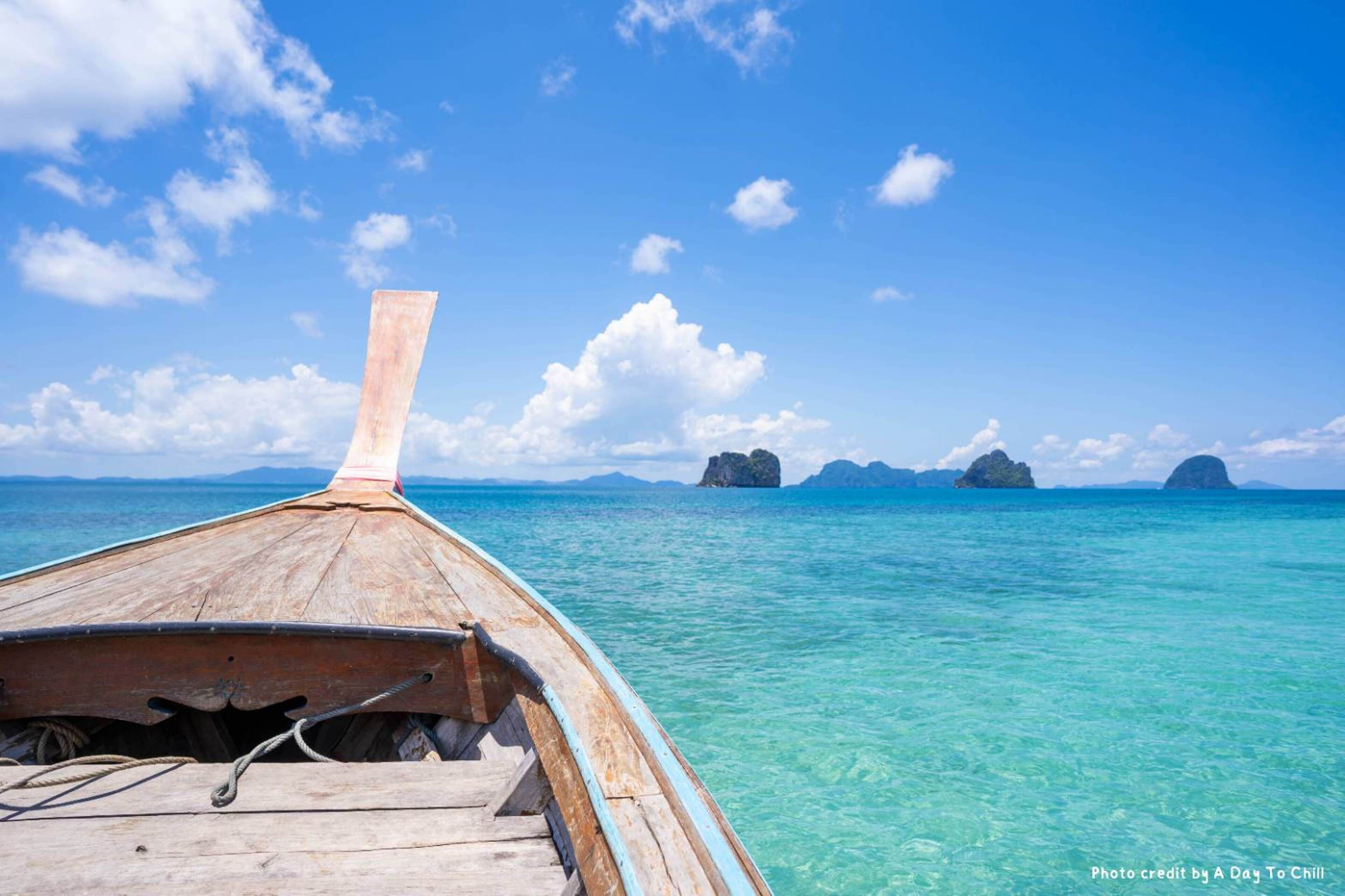 A wooden boat with a view of clear turquoise water and distant islands.