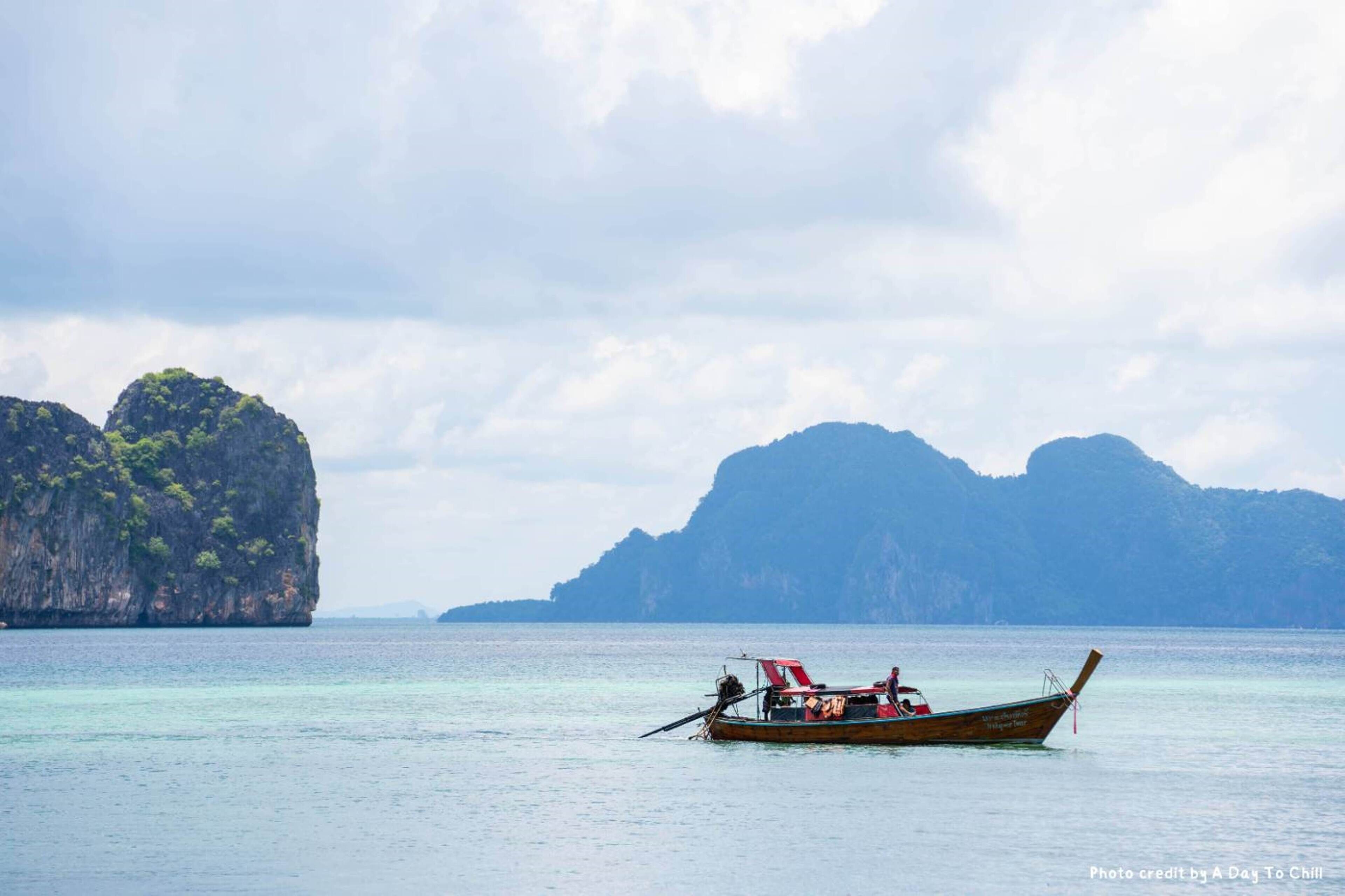 A boat with passengers and a mountainous landscape in the background.