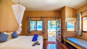 Un dormitorio con cama, un banco y vista a la playa.