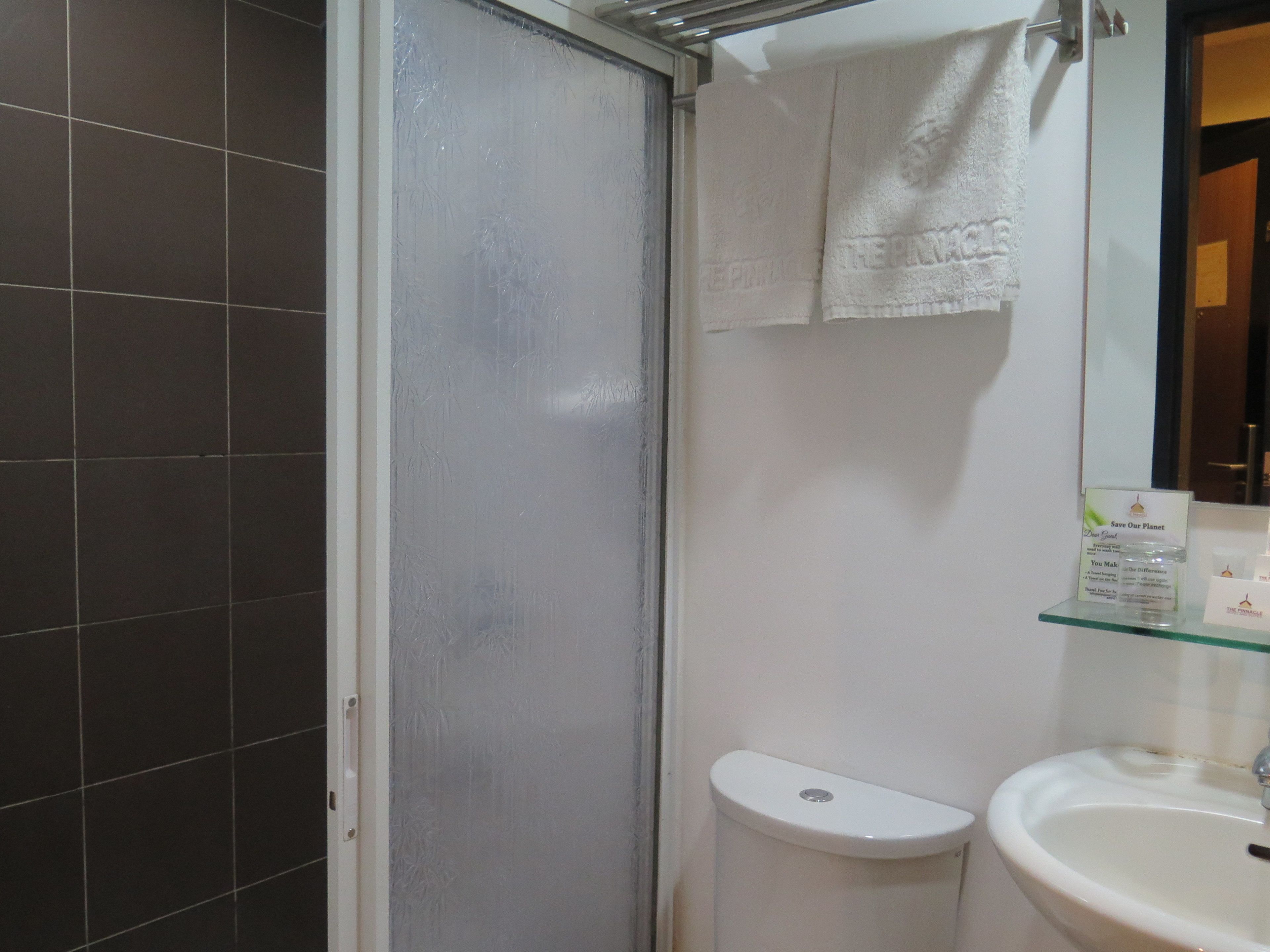 Une salle de bain équipée de toilettes, d’un lavabo et d’une porte de douche en verre dépoli.