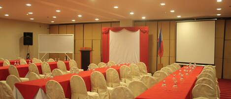 A conference room with rows of tables, chairs, and a projection screen.