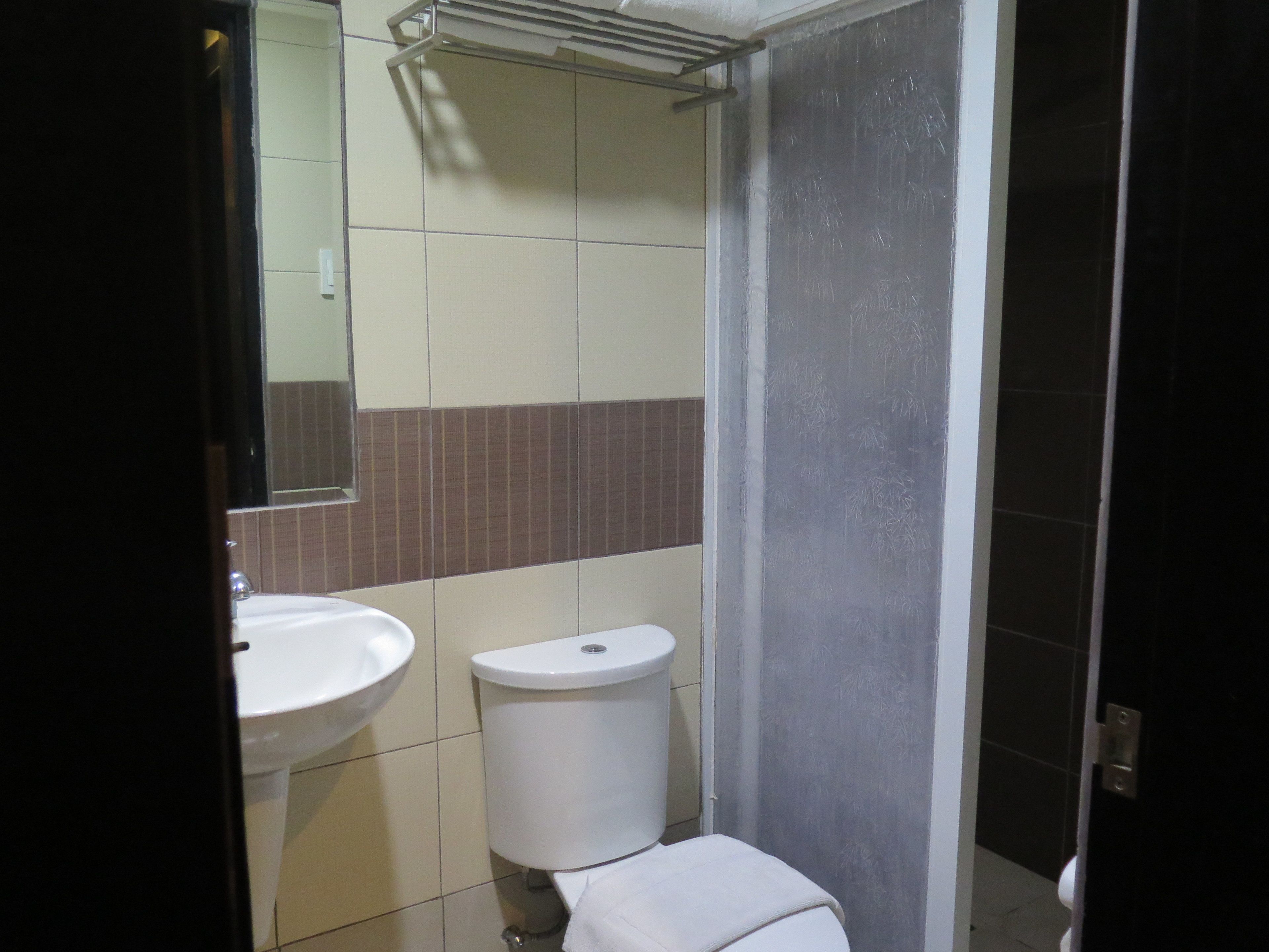 Une salle de bain avec un lavabo blanc, des toilettes et un miroir.