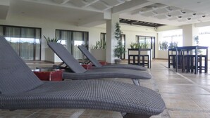 A modern indoor lounge area with reclining lounge chairs, a dining table, and potted plants. - The Pinnacle Hotel and Suites (Davao)