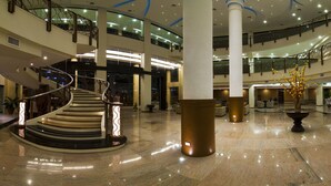 A spacious lobby with a central staircase, multiple floors, and a reception area with a curved counter. - The Pinnacle Hotel and Suites (Davao)