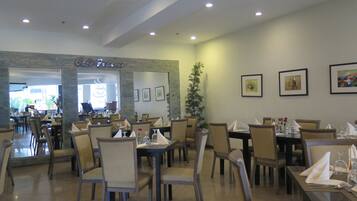 A restaurant with multiple tables and chairs, a coffee bar, and framed artwork on the walls.