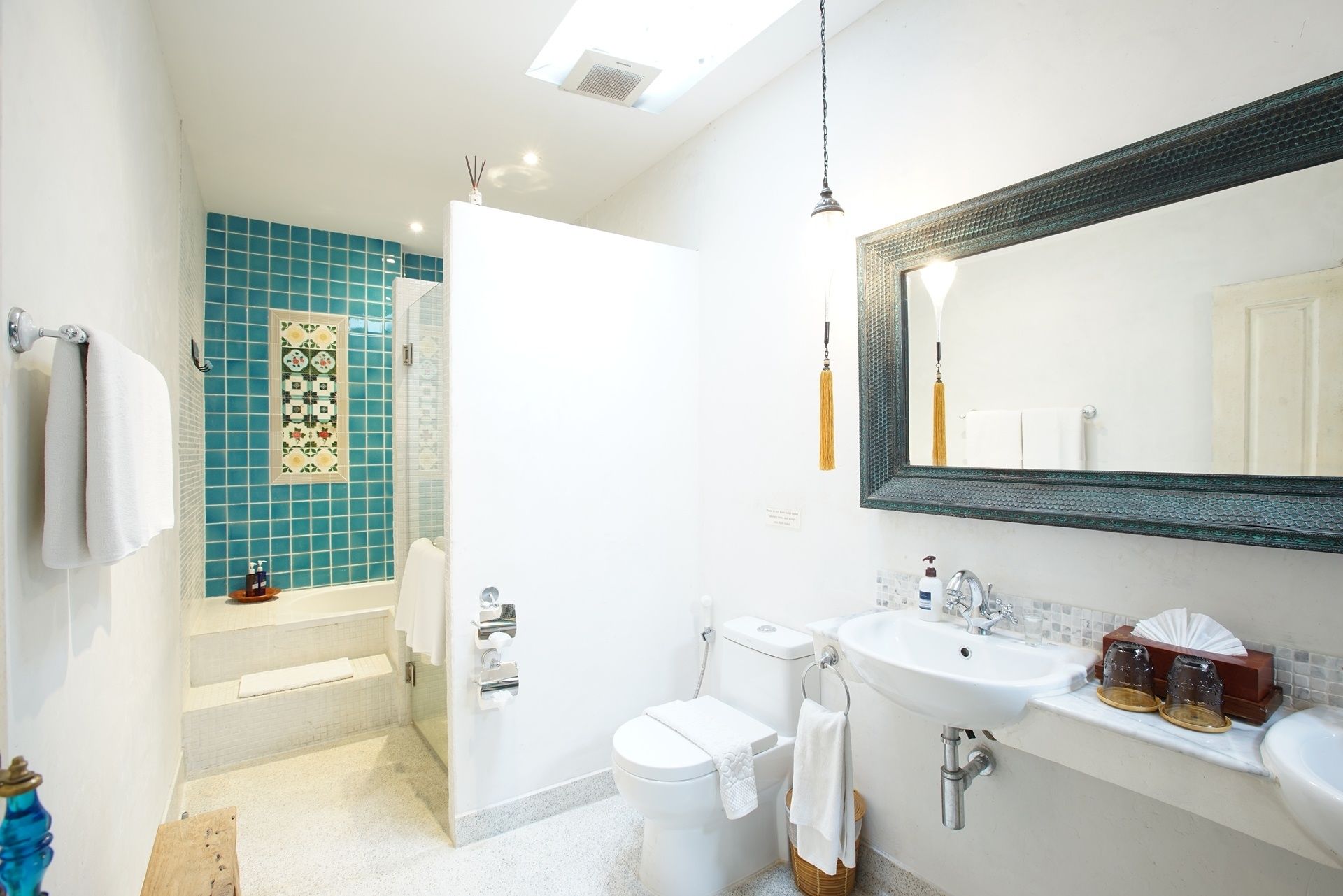A bathroom with a bathtub, toilet, sink, and a large mirror.