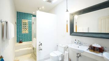 A bathroom with a bathtub, toilet, sink, and a large mirror.