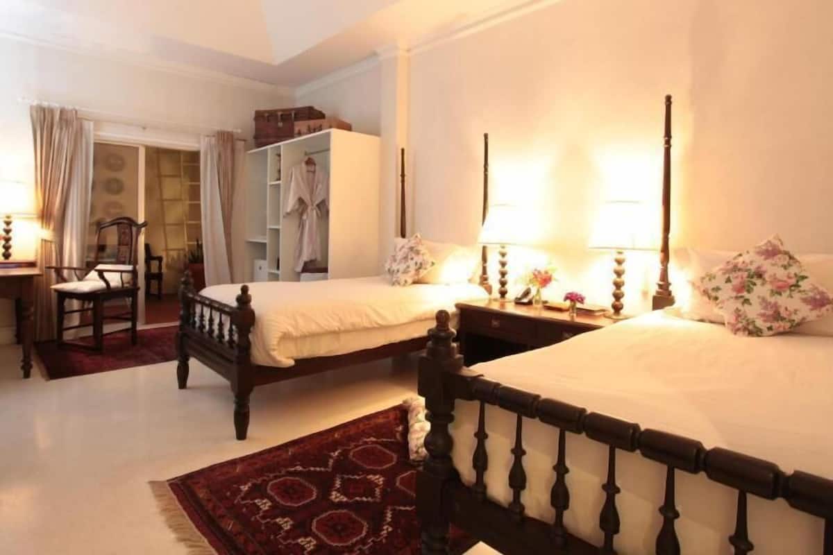 A bedroom with two beds, a wardrobe, a chair, and a mirror.