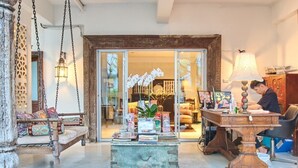 A cozy interior with a swing chair, a vintage chest of drawers, and a desk with a lamp. - At Niman Conceptual Home (Chiang Mai)