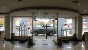 A hotel entrance with a glass door, a reception desk, and a car parked outside.