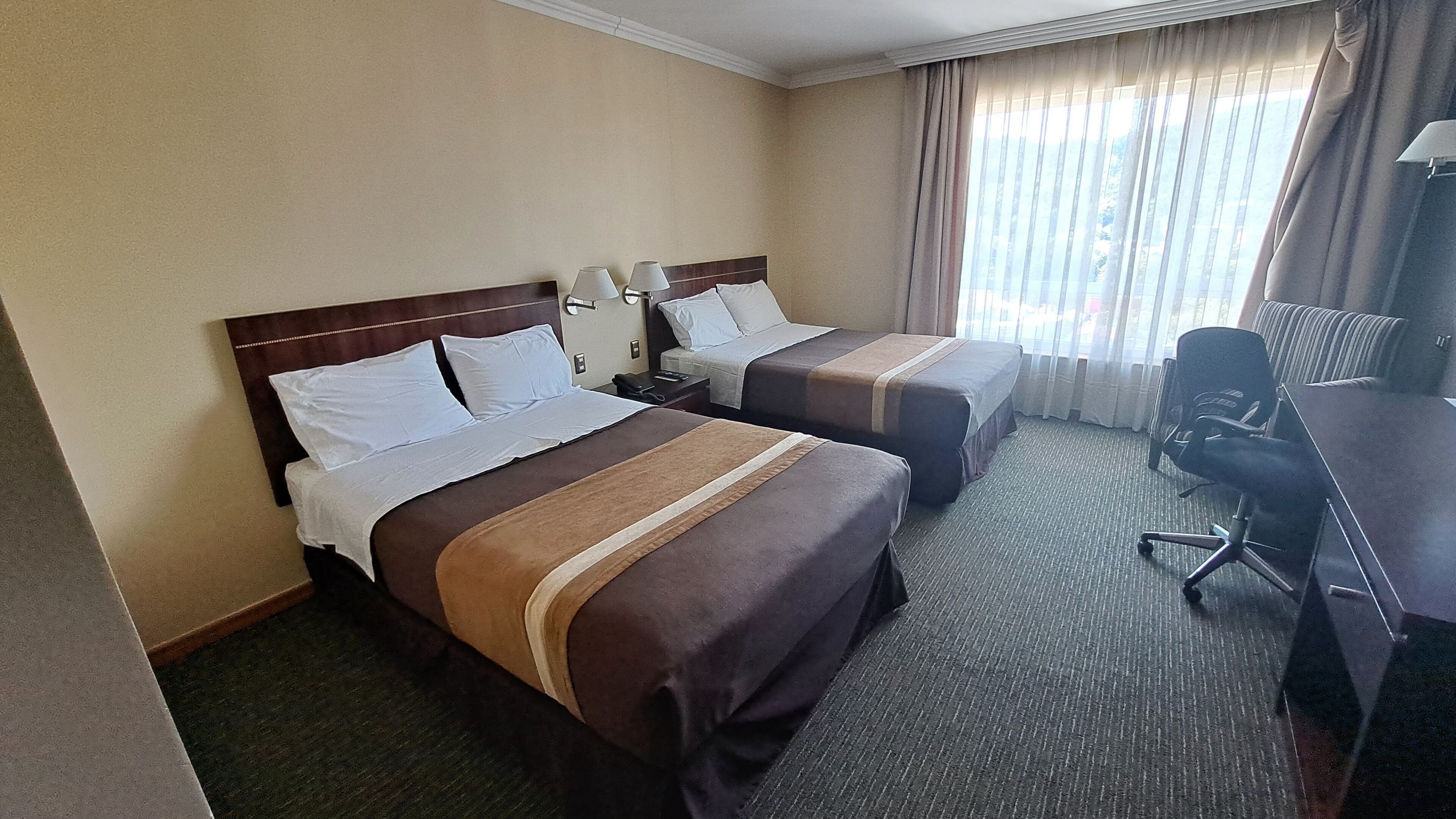 Una habitación de hotel con dos camas, un escritorio y una silla.