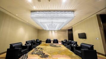 A conference room with a large, patterned carpet, black leather sofas, and a ceiling light fixture.