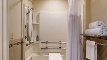 A bathroom with a bathtub, shower, and a toilet. There are towels and toiletries visible.