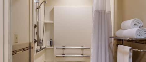 Un baño con bañera, ducha e inodoro. Se ven toallas y artículos de aseo.