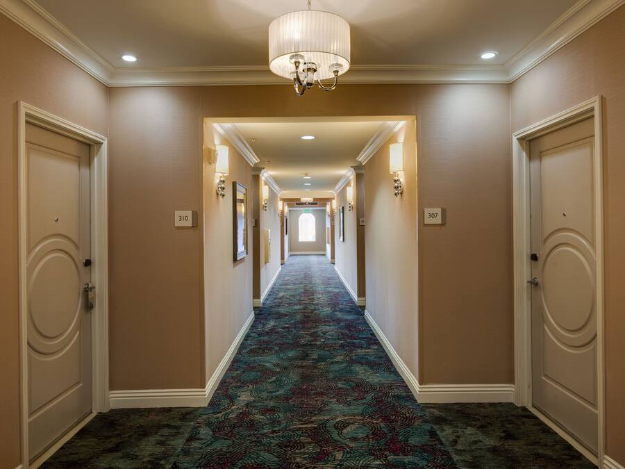 A hotel hallway with a patterned carpet, cream-colored walls, and doors numbered 310 and 307.