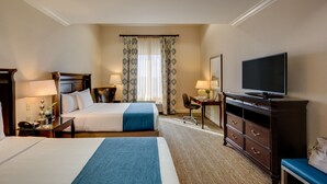Een hotelkamer met twee bedden, een bureau, een stoel, een televisie en een dressoir.