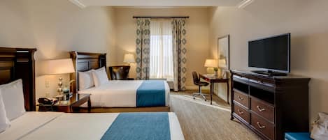 A hotel room with two beds, a desk, a chair, a TV, and a dresser.