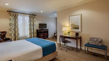 A hotel room with a bed, desk, chair, and a TV.